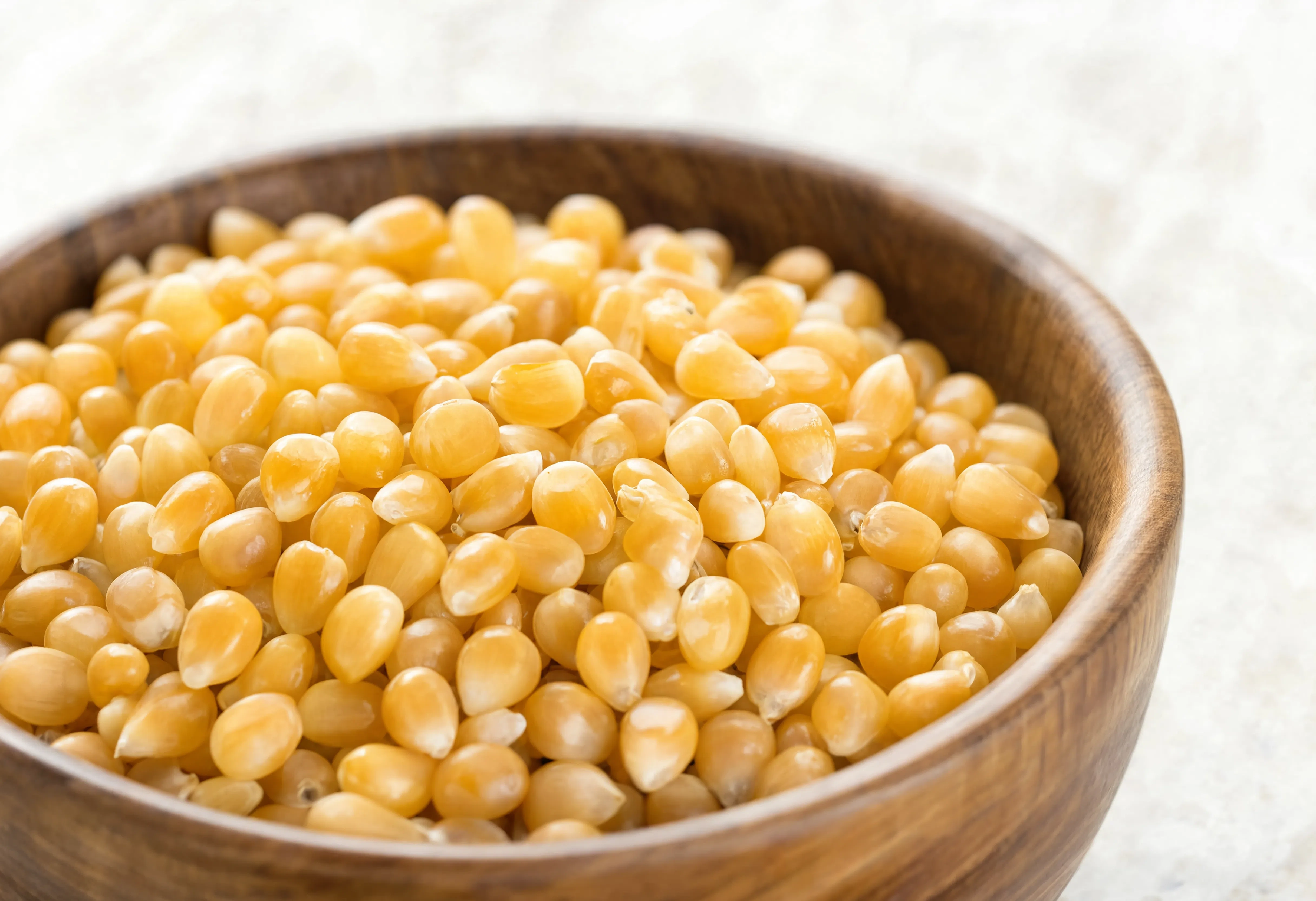 Yellow popcorn kernels in a wooden bowl